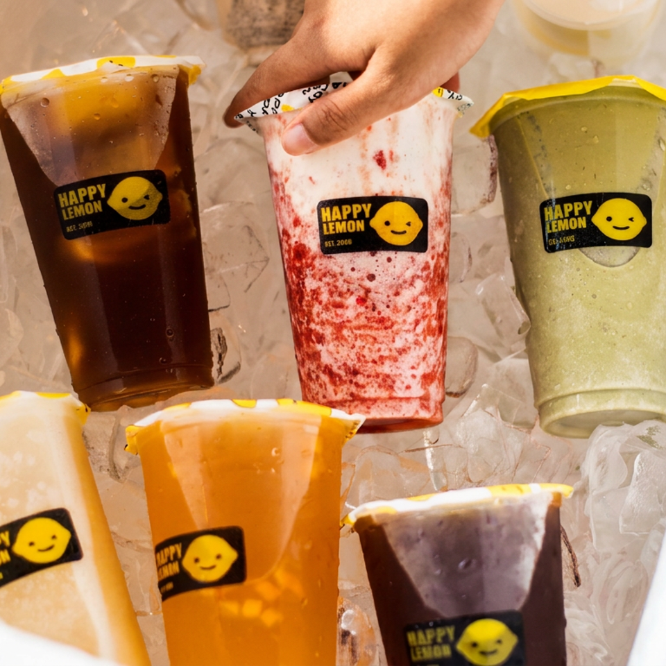 Five colorful Happy Lemon drinks chill on ice, including dark tea, berry, green, creamy, and orange beverages.